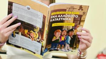 Δύο παλάμες που κρατάνε ένα ελληνικό παιδικό βιβλίο με τίτλο «Ένα Αλλόκοτο Κατάστημα» με εικονογραφημένους χαρακτήρες στο εξώφυλλο και πολύχρωμο κείμενο. Το βιβλίο είναι ανοιχτό, δείχνοντας τόσο το μπροστινό όσο και το πίσω εξώφυλλο.